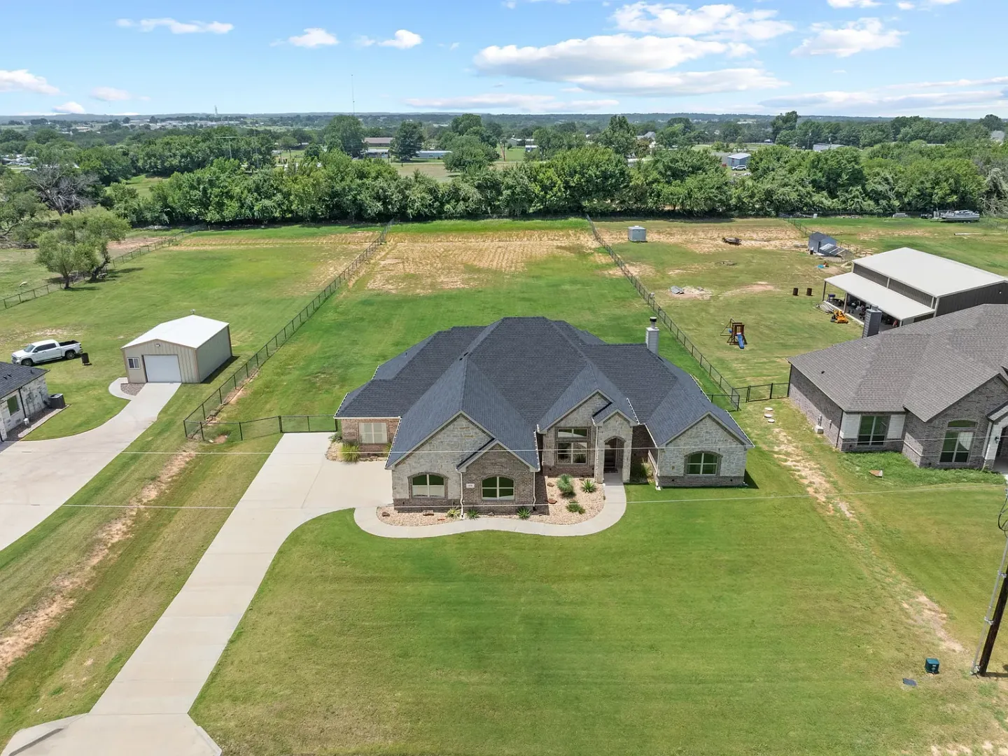 Backyard view of a completed Class 4 architectural shingle roof replacement on Agnes N St in Springtown, TX 76082 — RoofDog residential roofing project on a brick home with pool and mature trees