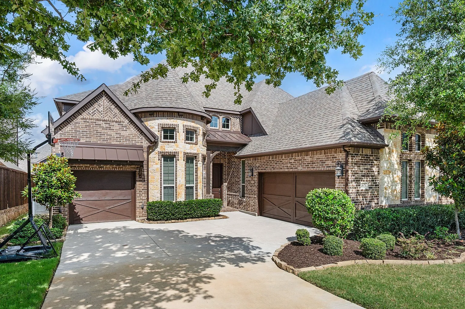 Finished roof installation on Huron Drive in Grapevine, TX 76051 — brick and stone luxury home with multi-pitch architectural shingles by RoofDog