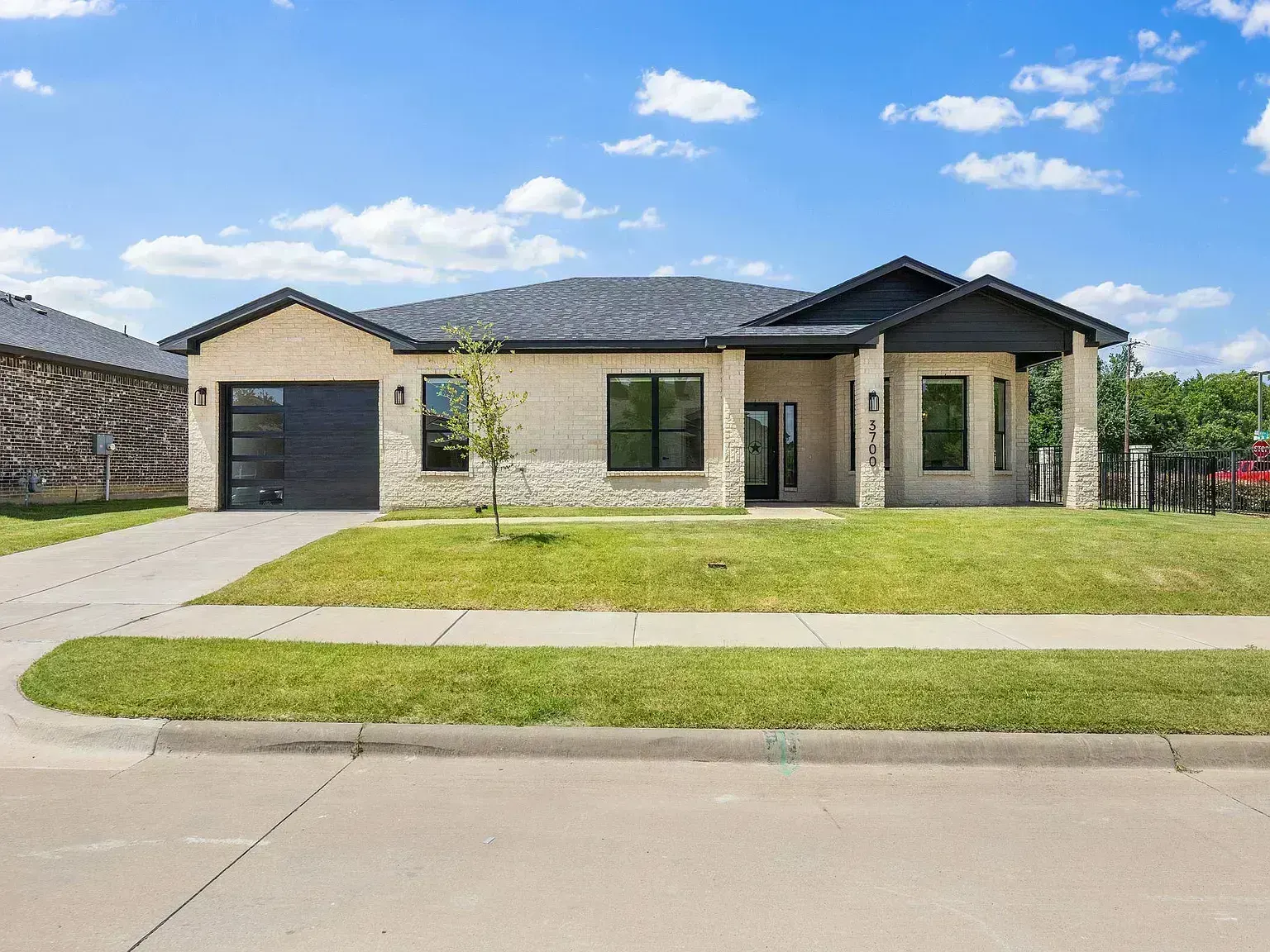 Completed roof installation on Creek View Drive in McKinney, TX 75071 — modern ranch-style home with stone and dark wood accents, charcoal architectural shingles by RoofDog