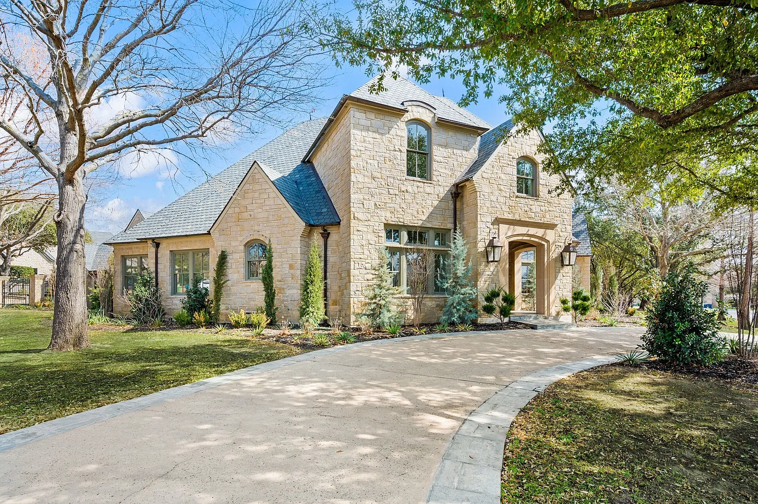 Luxury French country estate in Westlake, TX 76262 with a completed premium synthetic slate roof replacement by RoofDog — limestone facade, turret roofline, and mature tree canopy